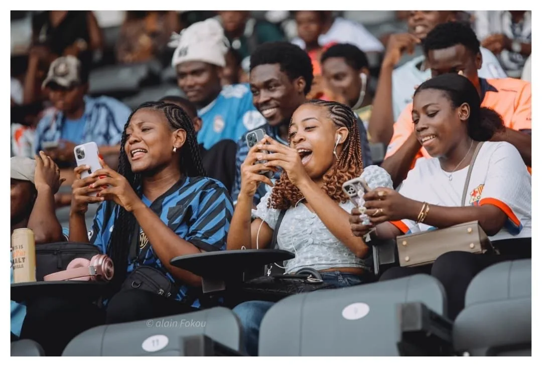 Des spectateurs sourient et filment depuis les tribunes.